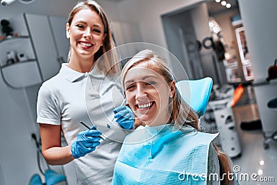 Portrait of a woman with toothy smile sitting at the dental chair with doctor on the background at the dental office Stock Photo