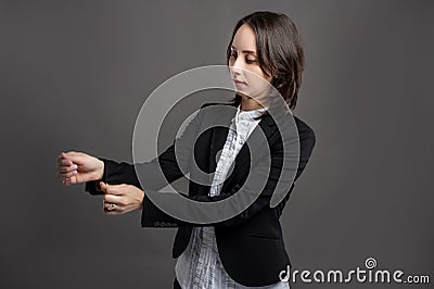 Portrait of wonderful young business woman arranges her suit sleeve, poseing on isolated gray background Stock Photo