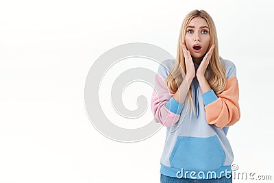 Portrait of worried, scared blond european girl, hold hands near face, gasping and open mouth, staring concerned camera Stock Photo