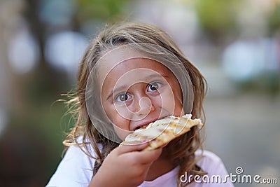portrait of 4 year old girl eating a piece of pizza Stock Photo