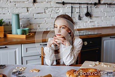 Portrait of a 10-year-old girl sitting in the kitchen. The child is having breakfast at the table Stock Photo