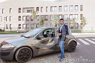 Portrait of young adult bearded insurance agent standing with positive facial expression near wrecked car and showing thumb up, Stock Photo