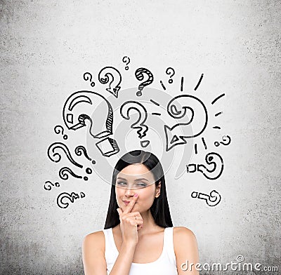 A portrait of a young artful brunette lady who is trying to find out a solution of some problem. The lady is in a white tank top. Stock Photo