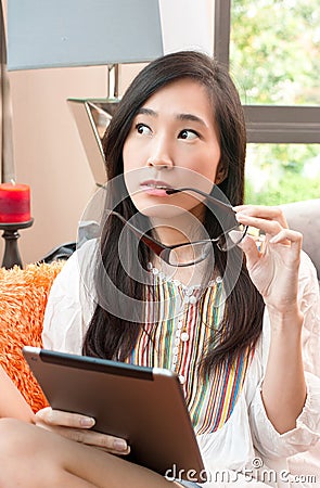 Portrait of young asian beautiful surprising woman is thinking while holding tablet Stock Photo