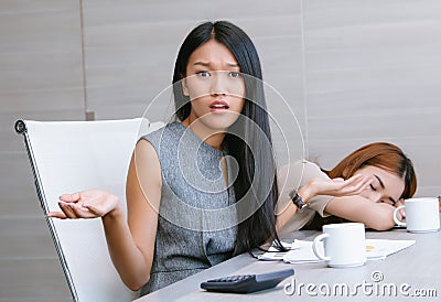 Portrait of young Asian businesswoman with arms out, shrugging her shoulders,saying: who cares, while workplace during work Stock Photo