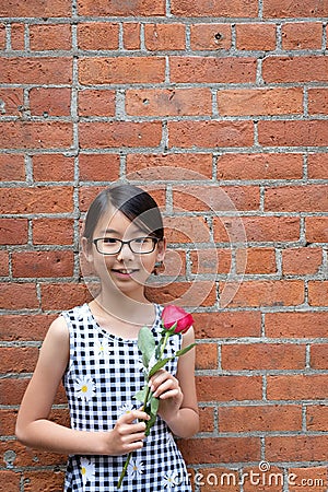 Portrait of young Asian girl with red rose flower against red brick wall Stock Photo