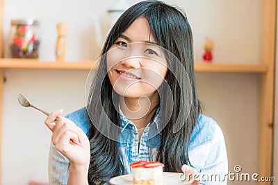 Portrait of young asian pretty smiling woman eating cake at cafe Stock Photo