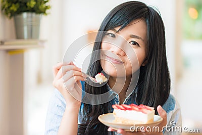 Portrait of young asian pretty smiling woman eating cake at cafe Stock Photo