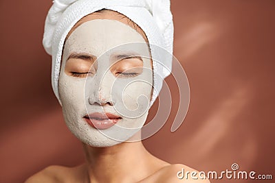 Portrait of young Asian wearing clay mask over brown background Stock Photo