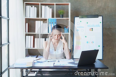Portrait of a young Asian woman showing acute headache from sitting for a long time at work. Stock Photo