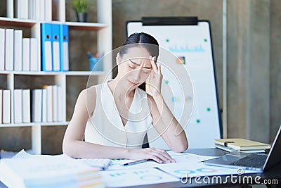 Portrait of a young Asian woman showing acute headache from sitting for a long time at work. Stock Photo