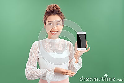 Portrait of young Asian woman showing her blank sreen mobile phone. Isolated over green background Stock Photo