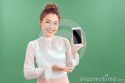 Portrait of young Asian woman showing her blank sreen mobile phone. Isolated over green background Stock Photo