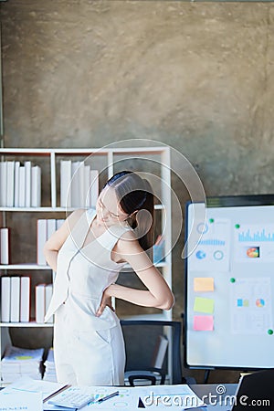 Portrait of a young Asian woman suffering from acute back pain from sitting for a long time at work. Stock Photo