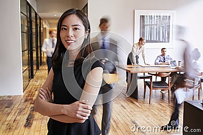 Portrait of young Asian woman in a busy modern workplace Stock Photo