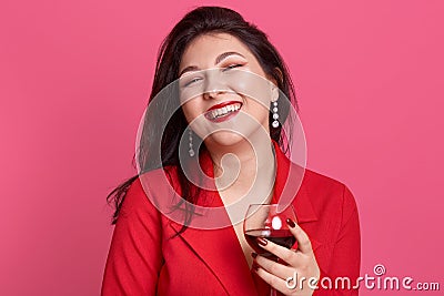 Portrait of young attractive brunette woman with glass of white wine in hands, lady posing isolated over pink studio background, Stock Photo