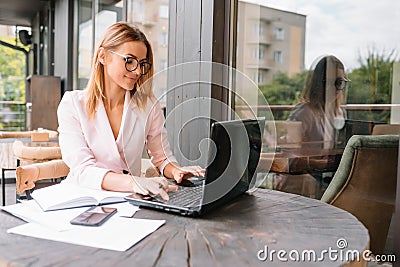 Portrait of young attractive businesswoman examining paperwork in bight light office interior sitting next to the window Stock Photo