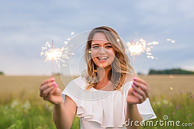 Portrait of young attractive celebrating woman holding sparkles. Stock Photo
