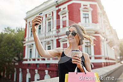 Portrait of young attractive feminine caucasian girl with dark hair in tan glasses and black dress smiling brightly Stock Photo