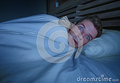 Portrait of young attractive scared man in fear and panic suffering horror nightmare or freezing feeling cold in Winter covering h Stock Photo