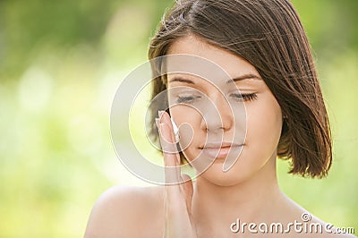 Portrait of young attractive woman putting cream on her face Stock Photo
