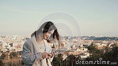 Portrait of young attractive woman standing at the panorama of Rome, Italy. Female use the smartphone outside. Stock Photo