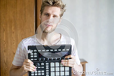 Portrait of young bearded man sound producer holding midi controller and headphones f Stock Photo