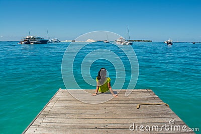 Portrait of young beautiful asian girl sitting at the pier looking at the ocean Stock Photo