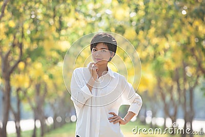 portrait of young beautiful asian woman with white shirt standing and smiling face in blur yellow flowers blooming background use Stock Photo