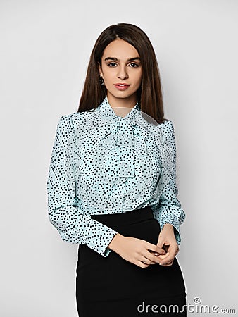 Portrait of young beautiful brunette business woman in stylish formal blouse shirt and black skirt over grey background Stock Photo