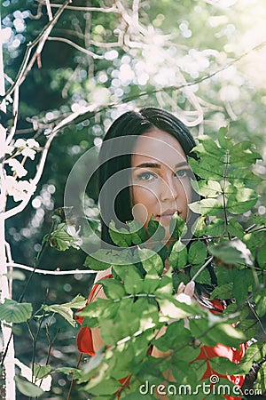 Portrait of a young beautiful brunette woman among green lush foliage. Vertical orientation Stock Photo