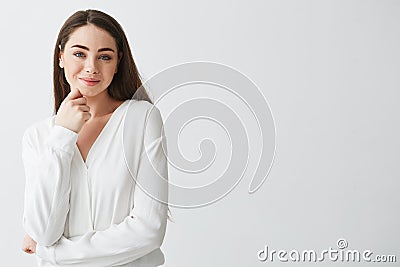 Portrait of young beautiful business lady looking at camera smiling touching face over white background. Stock Photo