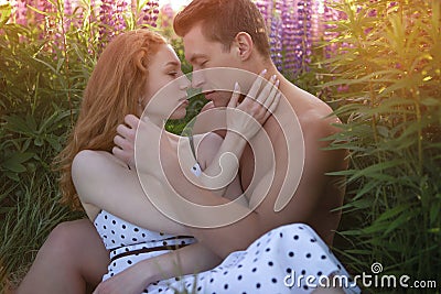 Portrait of a young beautiful couple gently embracing on a blooming field during sunset Stock Photo