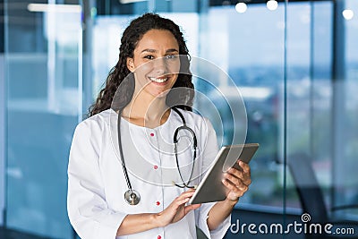 Portrait of young beautiful female doctor with tablet computer, Hispanic female doctor working in modern clinic office Stock Photo