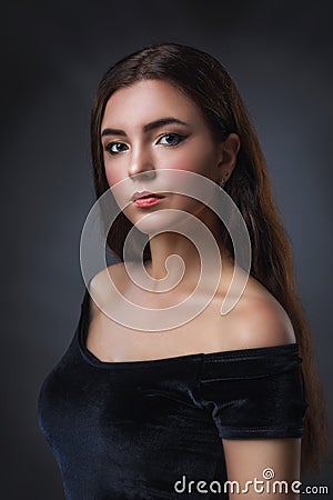 Portrait of a young beautiful girl in a black dress. Model with dark hair posing near the wall Stock Photo