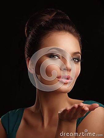 Portrait of a young beautiful girl with collected hair and expressive make up on the black background sends a kiss Stock Photo