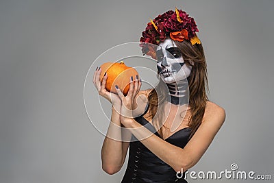 Portrait of young beautiful girl with fearful halloween skeleton makeup with a wreath Katrina Calavera made of flowers on her head Stock Photo