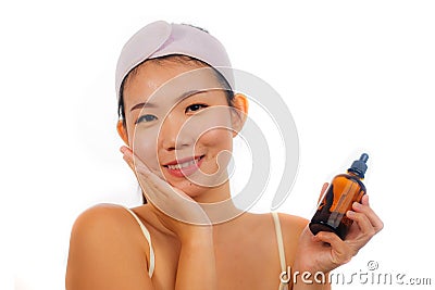 Young beautiful and happy Asian Chinese woman applying skincare wrinkle prevention serum treatment or aging beauty product on her Stock Photo