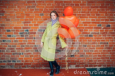 Portrait of young and beautiful lady in coat with red air balloons Stock Photo