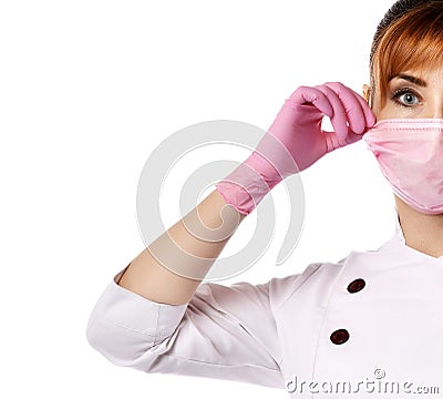 Portrait of young beautiful red-haired woman doctor or nurse in white special uniform and gloves putting mask on face Stock Photo