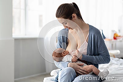 Portrait Of Young Beautiful Woman Breastfeeding Her Infant Child At Home Stock Photo