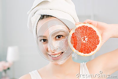 Portrait of young beautiful woman with healthy glow perfect smooth skin holds piece of grapefruit, white towel on the Stock Photo