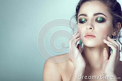 Portrait of young beautiful woman with perfect skin and bright make-up touching her face with manicured fingers. Stock Photo