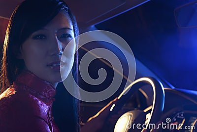 Portrait of young, beautiful woman in traditional clothing driving at night in Beijing Stock Photo
