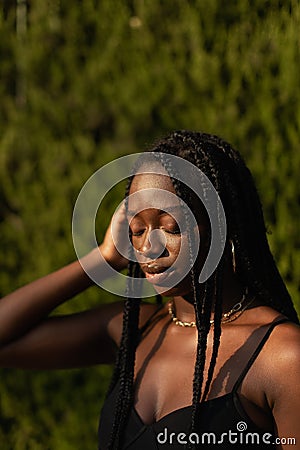 Portrait of a young black female removing her hair from her face whit her eyes closed Stock Photo