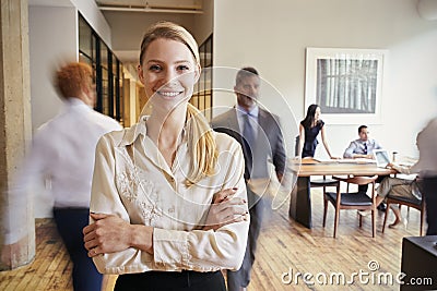 Portrait of young blonde woman in a busy modern workplace Stock Photo