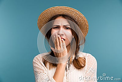 Portrait of a young bored girl in summer hat isolated over blue background, Stock Photo