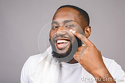 Portrait of young brutal african american man applying facial cream on his cheek. Close up portrait, men`s beauty. skin care Stock Photo