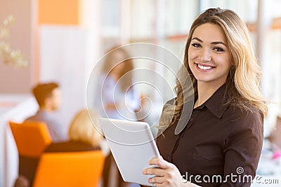 Portrait of young business woman at modern startup office interior, team in meeting in background Stock Photo