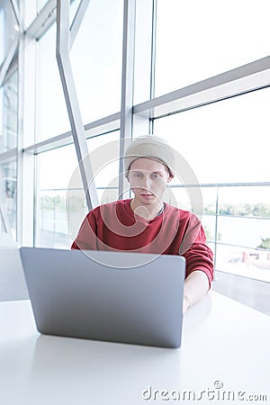 Portrait of a young businessman in casual clothing working on a laptop near a window Stock Photo